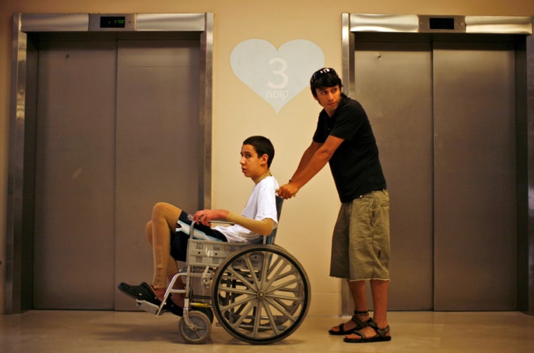 Ami Ortiz, injured when a booby-trapped gift for his family exploded in his home in March, is wheeled by his brother at Tel Hashomer Hospital in Tel Aviv on June 11.