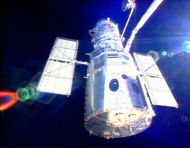 In a picture from 2002, the space shuttle Columbia's robot arm moves the Hubble Space Telescope out of the payload bay, at the end of what may have been the observatory's last repair job.