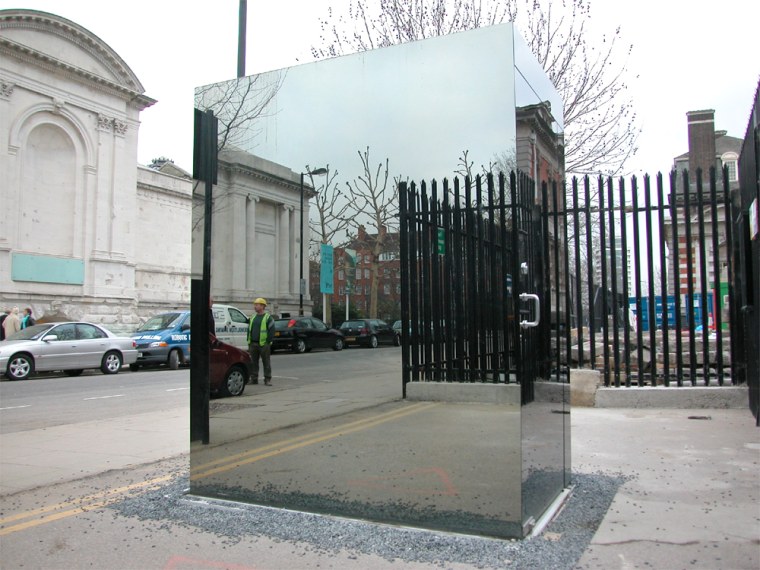 An art exhibit of a usable toilet enclosed in a cube of one-way glass is seen across the road from London's Tate Britain Museum. The person inside the outhouse can see passersby while remaining invisible to them.