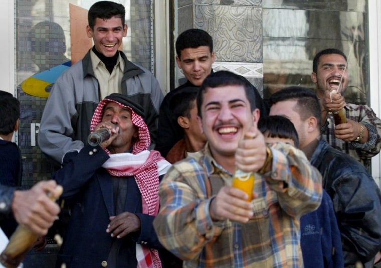 Iraqis in the southern city of Nasiriyah sprayed soft drinks Sunday to celebrate the capture of toppled Iraqi president Saddam Hussein. The ousted Iraqi president has been captured in a raid by US forces backed by Kurdish fighters in his northern hometown of Tikrit, a senior Kurdish official told AFP. AFP PHOTO/ABDELHAK SENNA