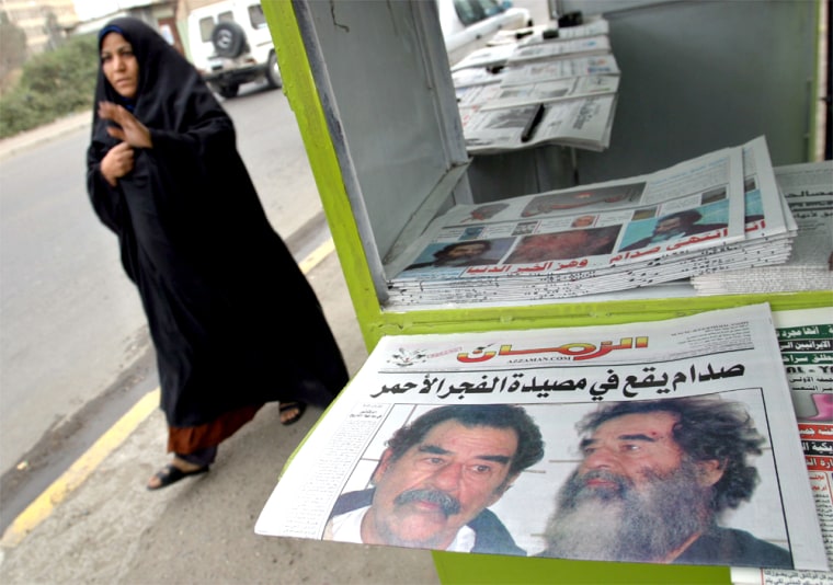 WOMAN PASSES BY IRAQI NEWSPAPER SHOWING SADDAM HUSSEIN IN BAGHDAD