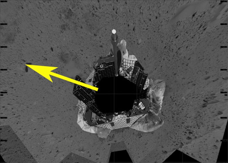 This mosaic image shows an overhead view of the Spirit rover as it prepares to roll off the lander. The yellow arrow illustrates the direction the rover may take to roll safely off the lander. The rover was originally positioned to roll straight forward off the lander, on the "south" side of image. However, an airbag is blocking its path. Over the next few days, the rover will turn itself 120 degrees.