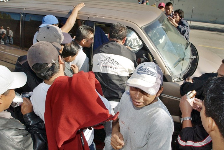 A dozen or more day laborers swarm a van, seeking work from the driver, outside the entrance to a Home Depot store, an area where undocumented immigrants are among those who gather for potential employers, in Los Angeles' Hollywood district Wednesday, Jan. 7, 2004. President Bush called Wednesday for a major overhaul of America's immigration system to grant legal status to millions of undocumented workers in the United States, saying the current program is not working.