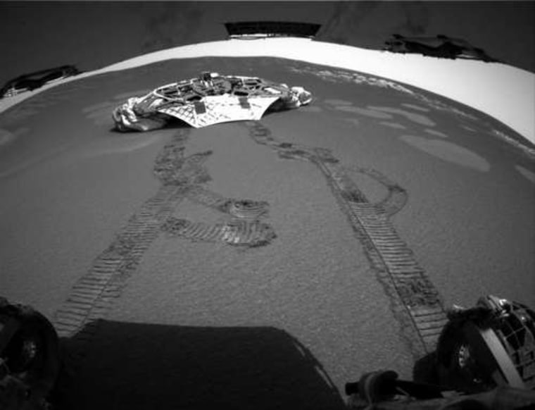 One of Opportunity's hazard avoidance cameras looks back at the rover tracks leading away from the landing platform. In the background, the "lilypad" marks left by the spacecraft's airbags are visible.