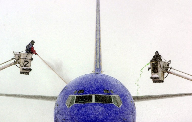Workers at Kansas City International Airport work to de-ice a Southwest Airlines flight Thursday. Heavy snow fell throughout the day causing school closings and slowing travel.