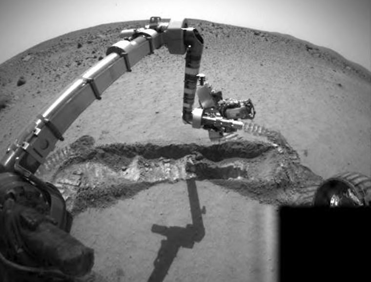 The Spirit rover positions its instrument-equipped robotic arm over the trench it dug in the soil of Mars' Gusev Crater. This view was captured by the NASA probe's hazard avoidance camera.