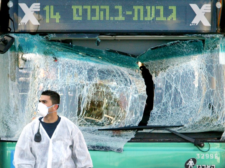 A police investigator stands in front of the shattered windows of a bus that was struck by a suicide bomber on Sunday in Jerusalem.
