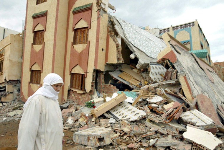 A woman passes by a collapsed building in the Moroccan town of Imzouren after an earthquake struck the northeastern part of the country early Tuesday.