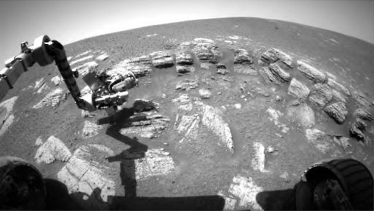 The Opportunity rover extends its robotic arm, bristling with scientific instruments, over Martian rocks and dirt. This picture was taken by the front hazard avoidance camera and released Wednesday.