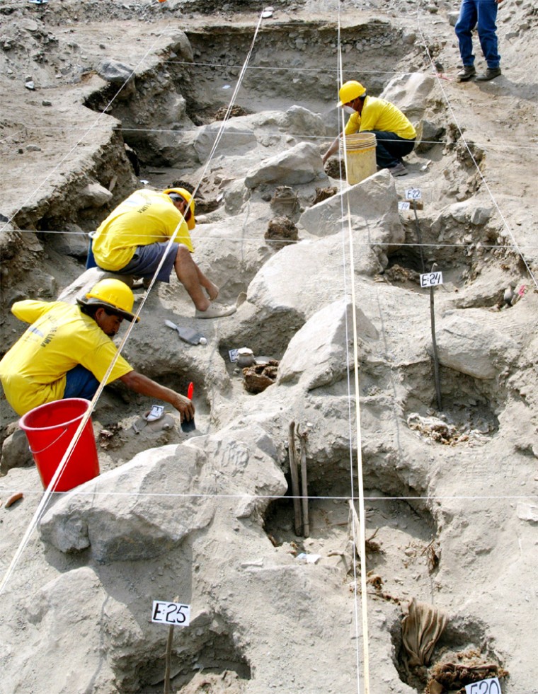 WORKERS EXCAVATE THE REMAINS OF ONE OF THE 26 MUMMIES IN THE OUTSKIRTS OF LIMA