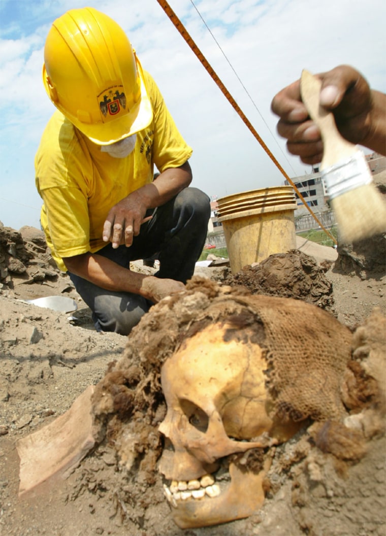 WORKERS CLEAN REMAINS OF ONE OF THE 26 MUMMIES IN THE OUTSKIRTS OF LIMA