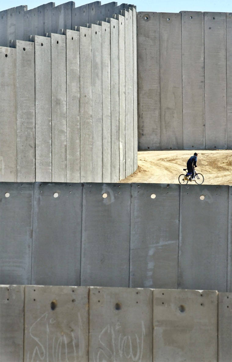AN PALESTINIAN BOY RIDES ON A BICYCLE NEAR A PART OF ISRAELS CONTROVERSIAL SECURITY BARRIER IN EAST JERUSALEM