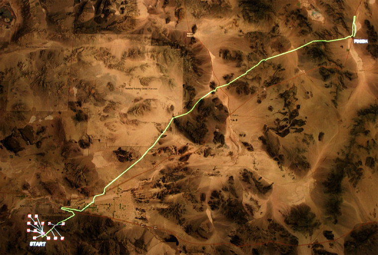 A countour map shows the 144 mile route for the DARPA Grand Challenge as a green line between Barstow, California and Prim, Nevada. The bright dots at lower left show the final positions of the robotic vehicles clustered around Barstow.