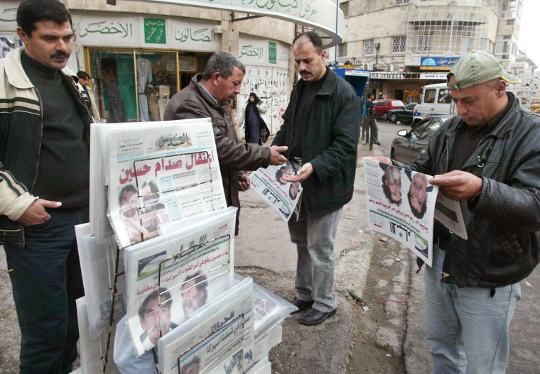 Palestinians read newspapers in the West Bank city of Ramallah 15 December 2003 reporting the capture of Sadam Hussein. Palestinian officials, whose leader Yasser Arafat backed Saddam in the 1991 Gulf War over Kuwait, remained tight-lipped about Hussein's capture. Six hundred US soldiers nabbed the elusive Iraqi leader late 13 December 2003, after finding him hiding in a tiny hole dug under a small hut, just 15 kilometers southeast of his native town of Tikrit.      AFP PHOTO / JAMAL ARURI