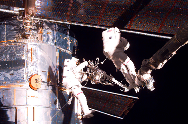 Spacewalkers Gregory Harbaugh, left, and Joseph Tanner work on the Hubble Space Telescope during a 1997 servicing mission. Harbaugh now says dooming Hubble to a premature end would be a "huge, huge mistake."
