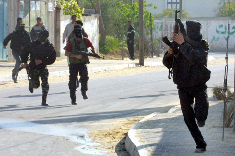 Masked Palestinian militants run to take cover during clashes with raiding Israeli forces in Khan Younis refugee camp, in the southern Gaza Strip, on Sunday.