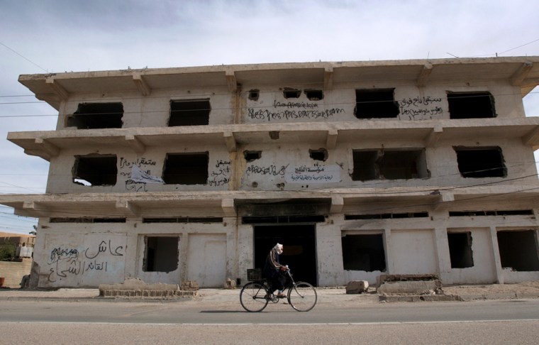 An Iraqi man cycles past a building previously used by U.S forces, and evacuated after several attacks, in Fallujah, west of Baghdad, on Thursday.