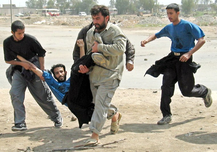 WOUNDED MAN IS CARRIED AFTER CLASHES WITH SPANISH LED FORCES NEAR NAJAF