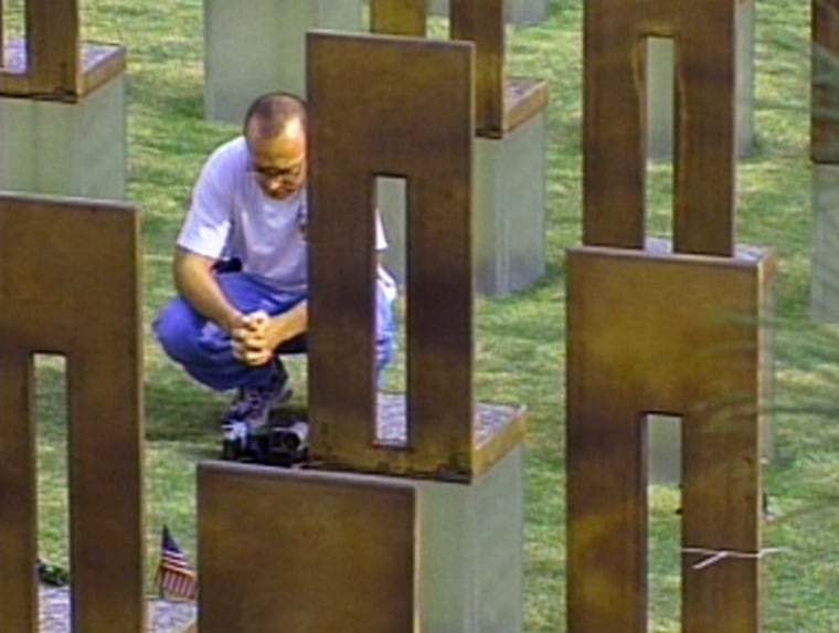 A man reflects Monday at the grave marker of a victim of the Oklahoma City bombing.