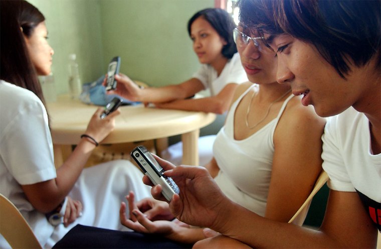 Filipino youth check their mobile phones for messages while at a school canteen in Manila.  