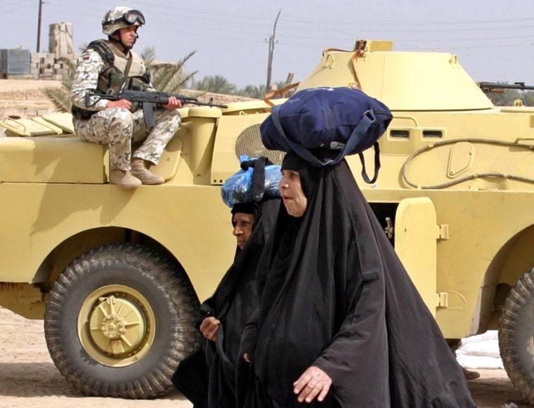 TWO IRAQI WOMEN WALK PAST A POLISH SOLDIER NEAR KERBALA