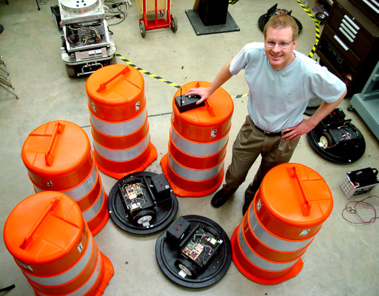 Shane Farritor, mechanical engineering professor at the University of Nebraska-Lincoln, shows off the robotic traffic barrels. The traditional orange-and-white tops fit over a black base that contains the electronics and motors.