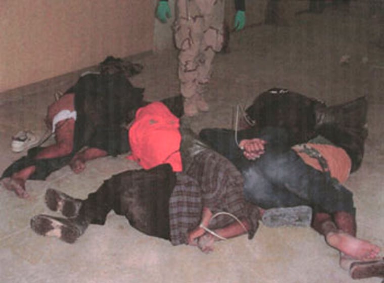 An American soldier surveys a group of bound Iraqi prisoners at the Abu Ghraib prison near Baghdad, Iraq in this undated photo. 