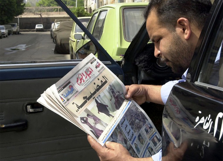An Egyptian taxi driver reads the Akhbar el-Yom newspaper on a Cairo street with images showing apparent abuse of Iraqi prisoners inside the Abu Ghraib prison. 
