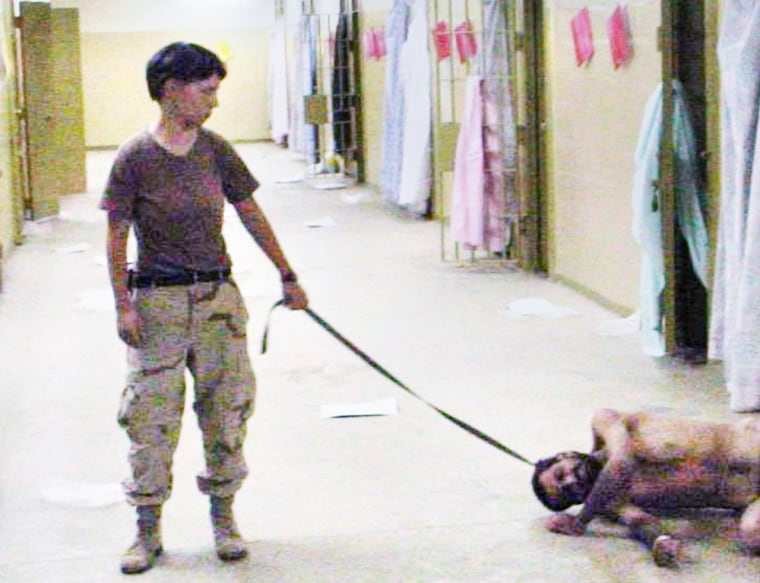 A naked detainee at the Abu Ghraib prison is tethered by a leash to prison guard Army Pvt. Lynndie England in this photograph.