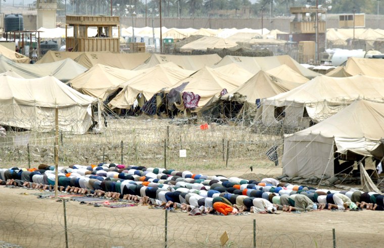 Inmates of the Abu Ghraib Prison kneel during traditional Friday prayers in the prison on the outskirts of Baghdad.