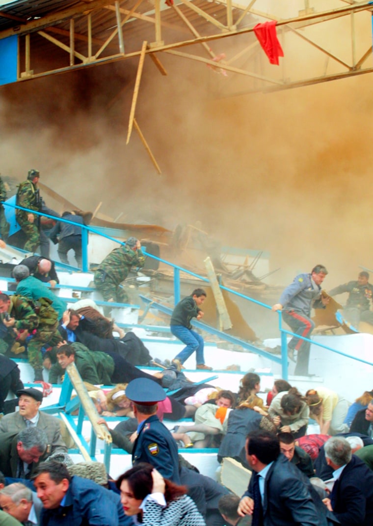 People run moments after an explosion which tore through a stadium in the Chechen capital where they were attending Victory Day observances, Grozny, Sunday, May 9, 2004.  The explosion happened underneath a VIP-seating area during a ceremony in the Dynamo stadium that was attended by senior Chechen officials. At least 10 people were killed, including President Akhmad Kadyrov, with 100 others injured.  (AP Photo/ Musa Sadulayev)