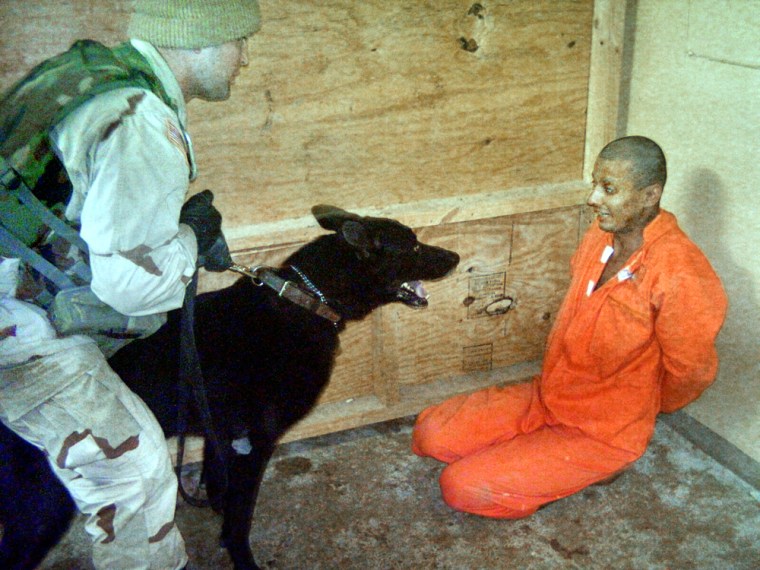 A U.S. soldier holds a dog in front an Iraqi detainee at Abu Ghraib prison on the outskirts of Baghdad.
