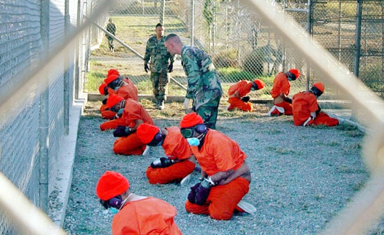 Detainees sit in a holding area at the U.S. Navy base at Guantanamo Bay, Cuba, during in-processing to the temporary detention facility in this Jan. 11, 2002 file photo.