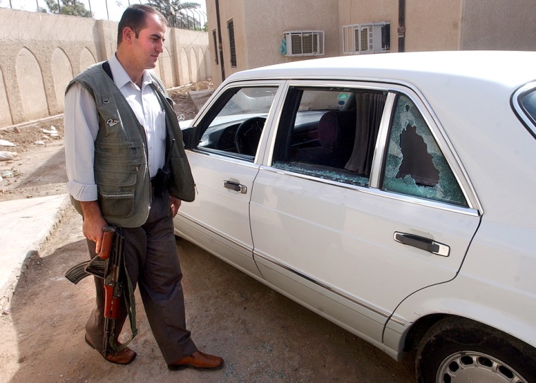 A security officer at the foreign ministry in Baghdad, Iraq walks past the bullet riddled car of deputy foreign minister Bassam Salih Kubba in which he was assassinated by gunmen Saturday June 12, 2004. The murder of Kubba, Iraq's most senior career diplomat, was the second assassination of a senior Iraqi figure in the past month. (AP Photo/Hussein Malla)