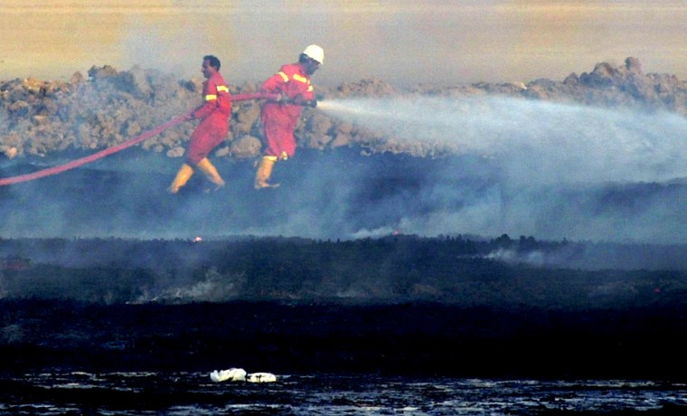 Iraqi firefighters try to extinguish a smouldering oil pipeline north of Faw, Iraq Tuesday June 15, 2004.  Explosions ripped through two oil pipelines in southern Iraq on Tuesday, cutting oil exports from the south by more than half, the Iraqi South Oil Company said.  (AP Photo/Nabeel al-Jurani)