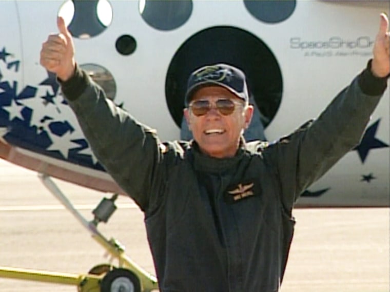 SpaceShipOne test pilot Mike Melvill, America's newest astronaut, flashes a broad grin and thumbs-up signs after emerging from his rocket plane.