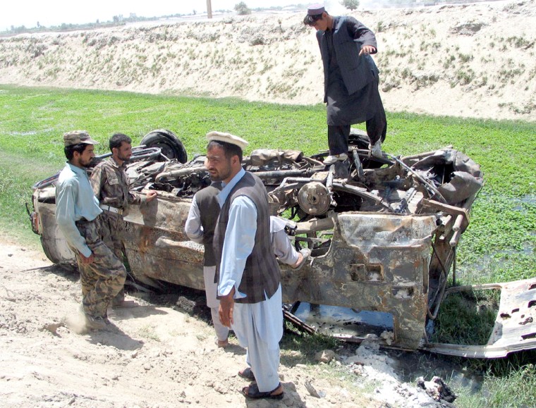 LOCALS LOOK AT A VAN DESTROYED BY A BOMB ON THE OUTSKIRTS OF JALALABAD