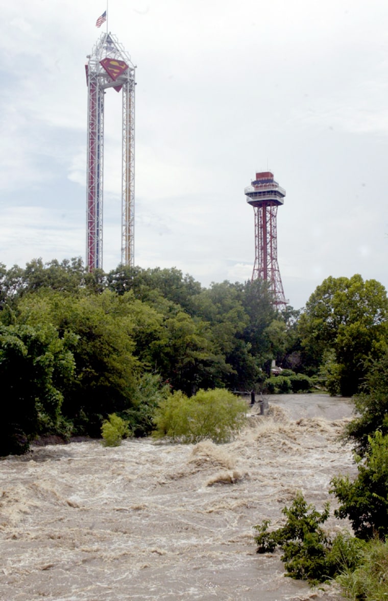 Floodwaters from a nearby creek rush through the grounds of Six Flags Over Texas in Arlington, Texas, on Tuesday. The amusement park was forced to close early, as brownish water rolled through. 