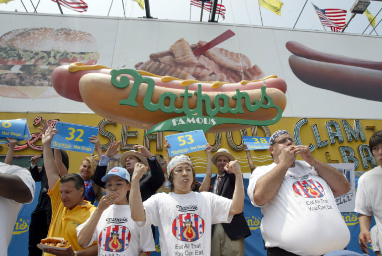Takeru Kobayashi, center, of Nagano, Japan, holds his hands up in victory after winning the Nathan's Famous hot dog eating contest in New York on Sunday.