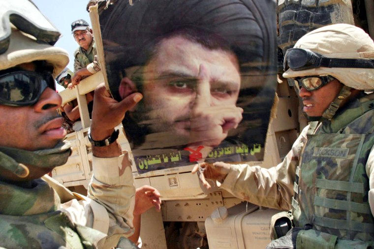 Members of the 1st Cavalry take a poster of Muqtada Al Sadr away from the Iraqi National Guardsmen that were patroling with them in the Sadr City neighborhood of Baghdad. 