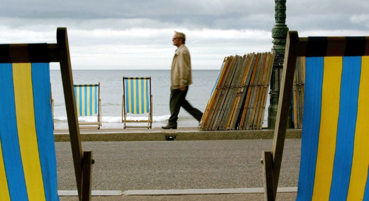 A pedestrian passes empty deckchairs on the beach at Bournemouth, England, on Thursday July 15, 2004, where the scene last year was crowded sands and hot temperatures. Spring has come and gone, fall is approaching- and Europeans from Oslo to Budapest are still waiting for summer. (AP Photo/PA, Chris Ison) ** UNITED KINGDOM OUT NO SALES MAGS OUT **