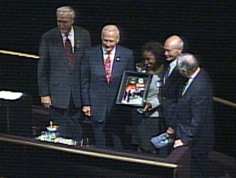 High-school senior Artesia Hughes displays one of the commemorative lunar plaques that were given to "Ambassadors of Exploration" during an Apollo 11 anniversary ceremony Tuesday in Washington. Hughes is surrounded by NASA Administrator Sean O'Keefe and Apollo 11 astronauts Buzz Aldrin, Michael Collins and Neil Armstrong.