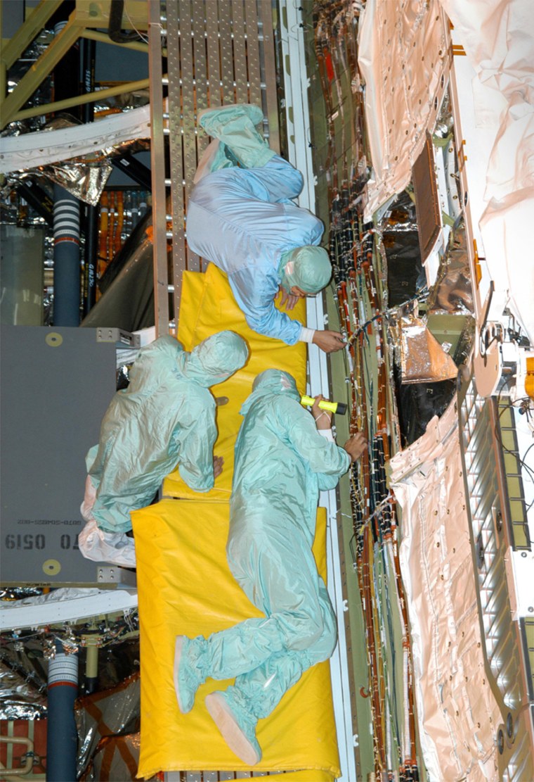 Workers check wiring during installation in the shuttle Discovery's cargo bay, in the Orbiter Processing Facility at NASA's Kennedy Space Center in Florida.