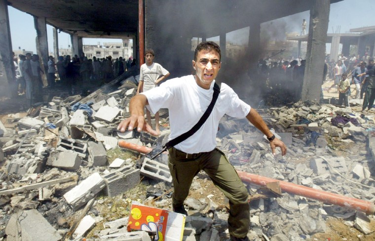 Palestinian runs in front a damaged house after Israeli helicopter missile strike in Gaza