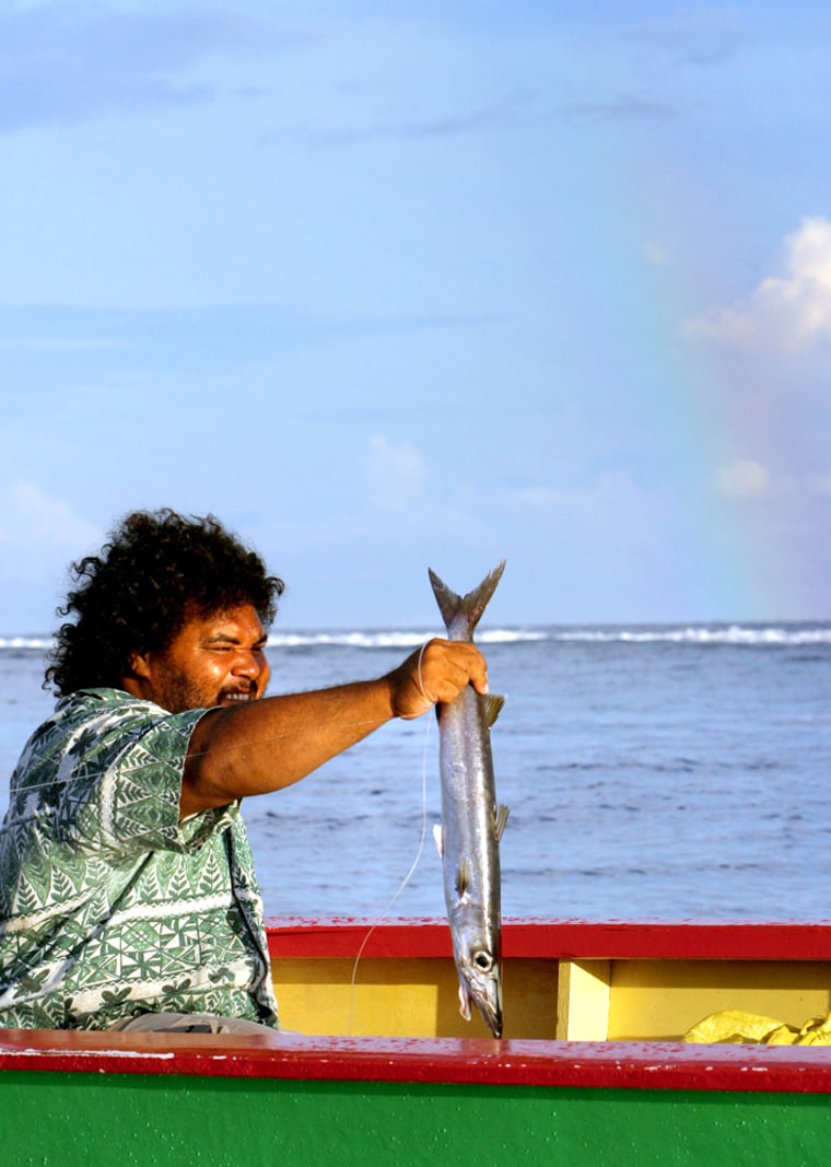 Tanemuga Tenae, a Tuvalu fisherman, holds up a skipjack tuna, his only catch from a morning's work at sea.