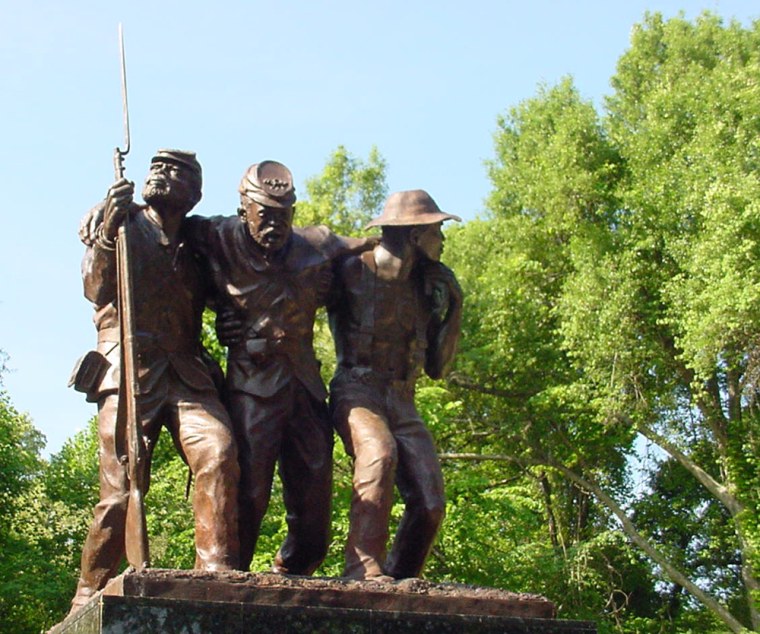 The African American monument consists of three bronze figures on a base of black African granite. Two of the figures are black Union soldiers, while the third is a common field hand. The field hand and one soldier support between them the second soldier who is wounded and represents the sacrifice in blood made by black soldiers on the field of battle during the Civil War. The field hand is looking behind at a past of slavery, while the first soldier gazes toward a future of freedom secured by force of arms on the field of battle.