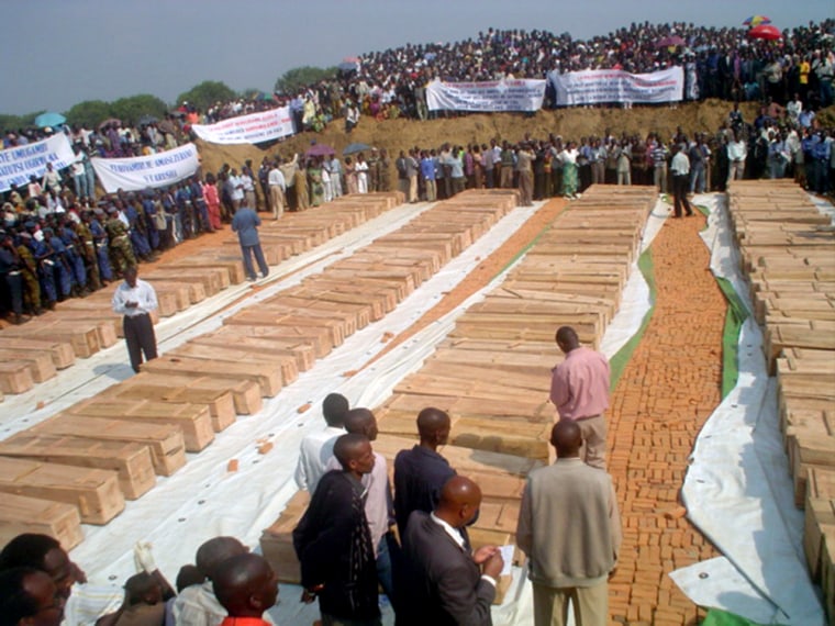 Mourners gather Monday, Aug. 16, 2004, around the coffins of 163 Congolese Tutsi massacred last weekend, at Gatumba, a U.N.-run refugee camp in Burundi. Burundi sealed the border with Congo and troop reinforcements were being moved in to head off further violence in the region.(AP Photo/Aloys Niyoyita)
