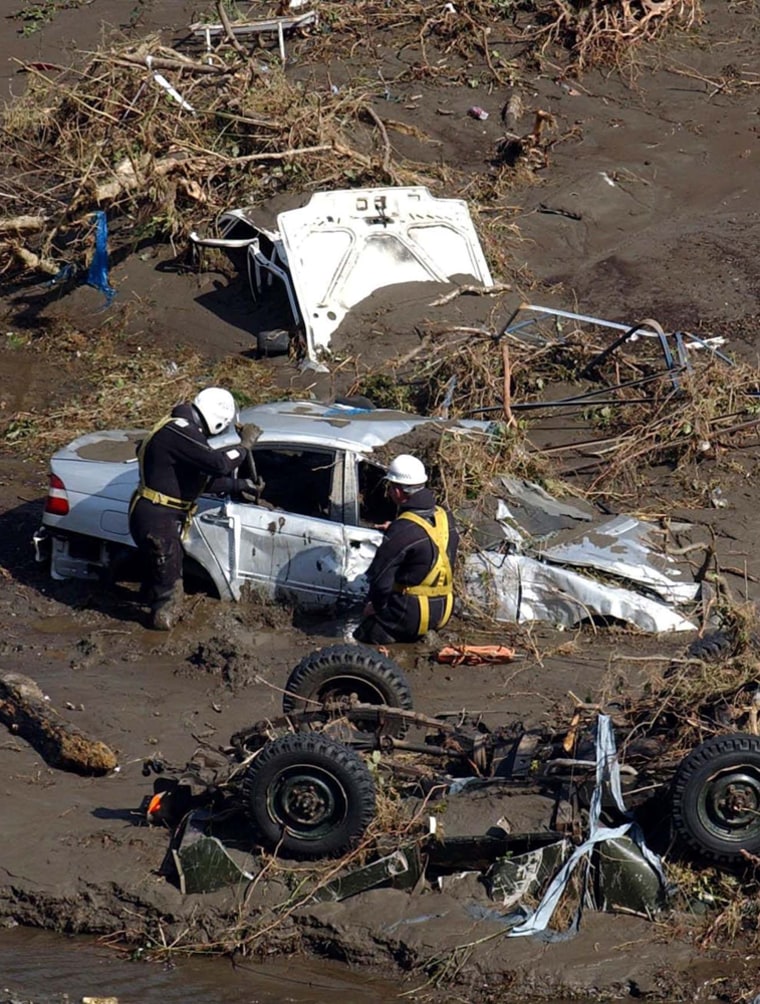 Workers from the emergency services examine vehicles in the Boscastle area of Cornwall, south west England, Tuesday Aug. 17, 2004, after a wall of water tore through the picturesque tourist spot on Monday.  Emergency workers are checking for possible victims of the flooding which was sparked by 2.4 inches (6 centimeters) of rainfall in just hours on Monday afternoon. (AP Photo/Barry Batchelor/PA)  **  UNITED KINGDOM OUT MAGS OUT NO SALES  **