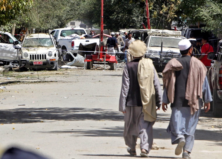 Afghan men walk near the site where a powerful bomb explosion occurred on Sunday in Kabul