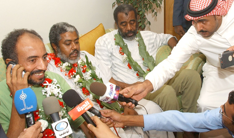 Freed Kenyan hostage Salm Faiz Khamis, left, talks on the phone to his family after arriving at Kuwait International Airport on Wednesday. Seated beside Salm are fellow hostages Jalal Mohammed Awadh, center, and Ibrahim Khamis. 